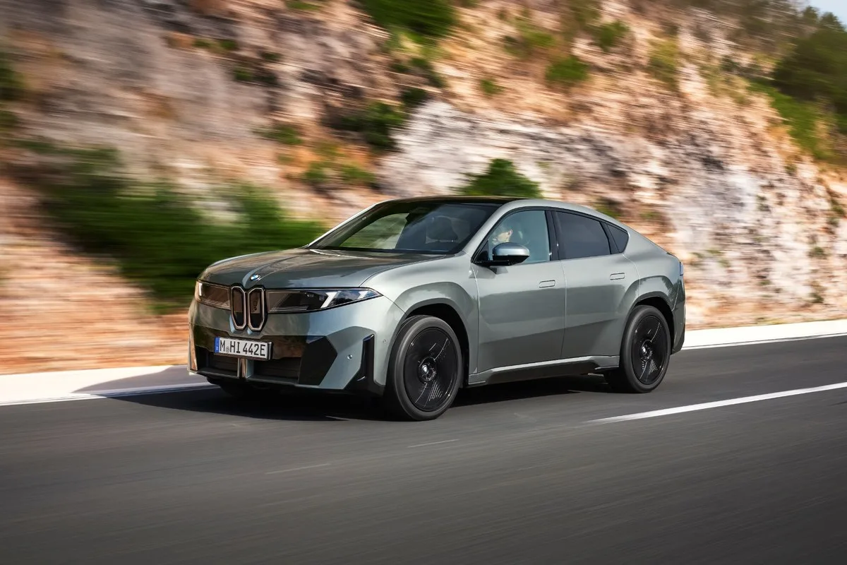 Grey BMW iX4 driving past a rock cutting