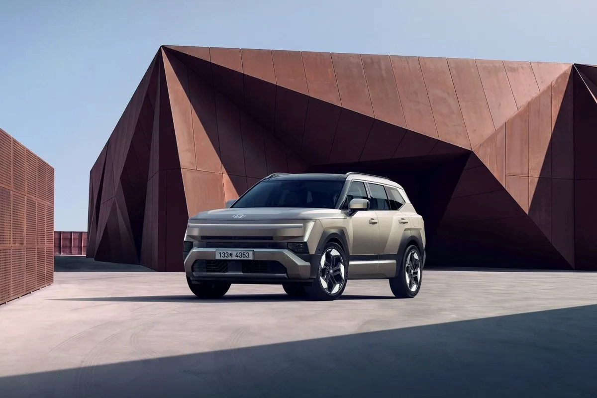 All-new Hyundai Tucson in beige parked in front of a rust-coloured steel building