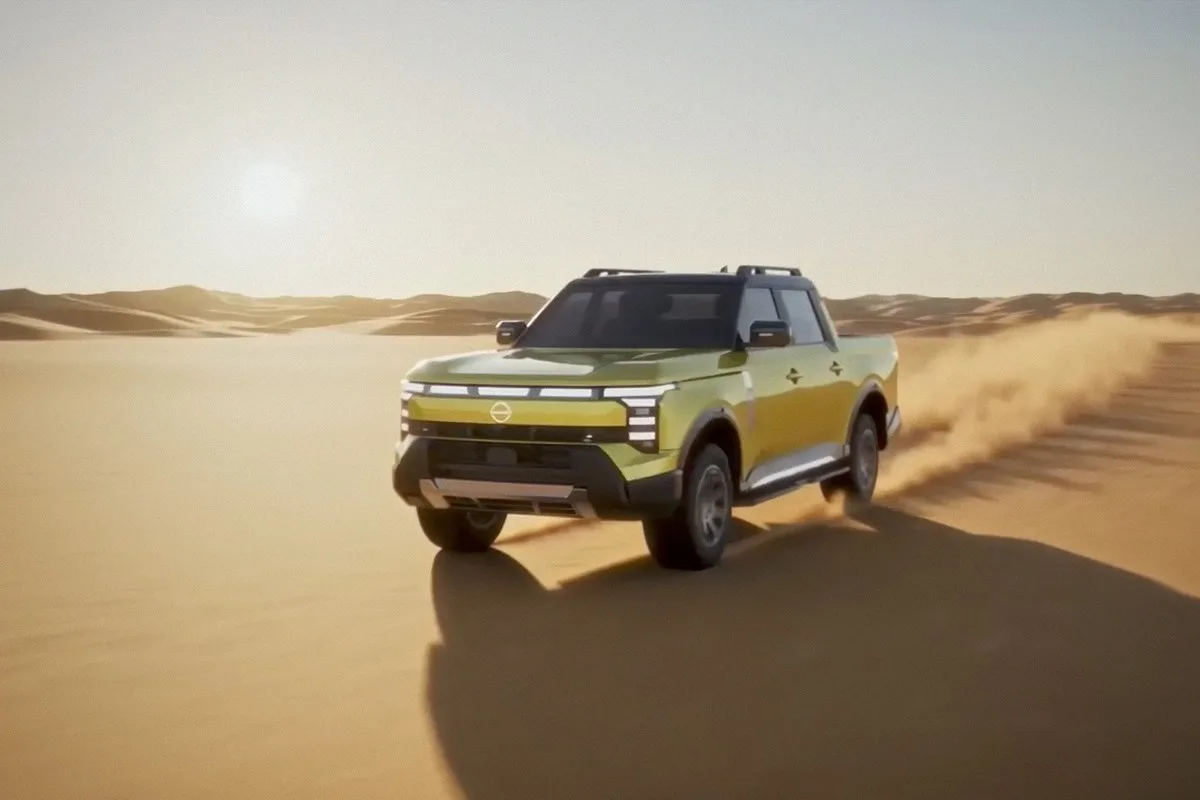 Yellow Nissan Navara Pro PHEV kicking up sand as it drives across desert dunes