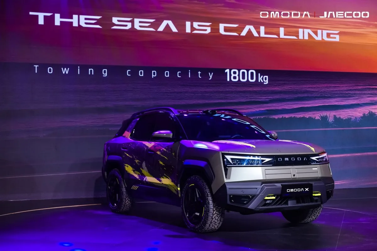 Omoda X front three-quarter view on the reveal stage in front of a beach sunset screen
