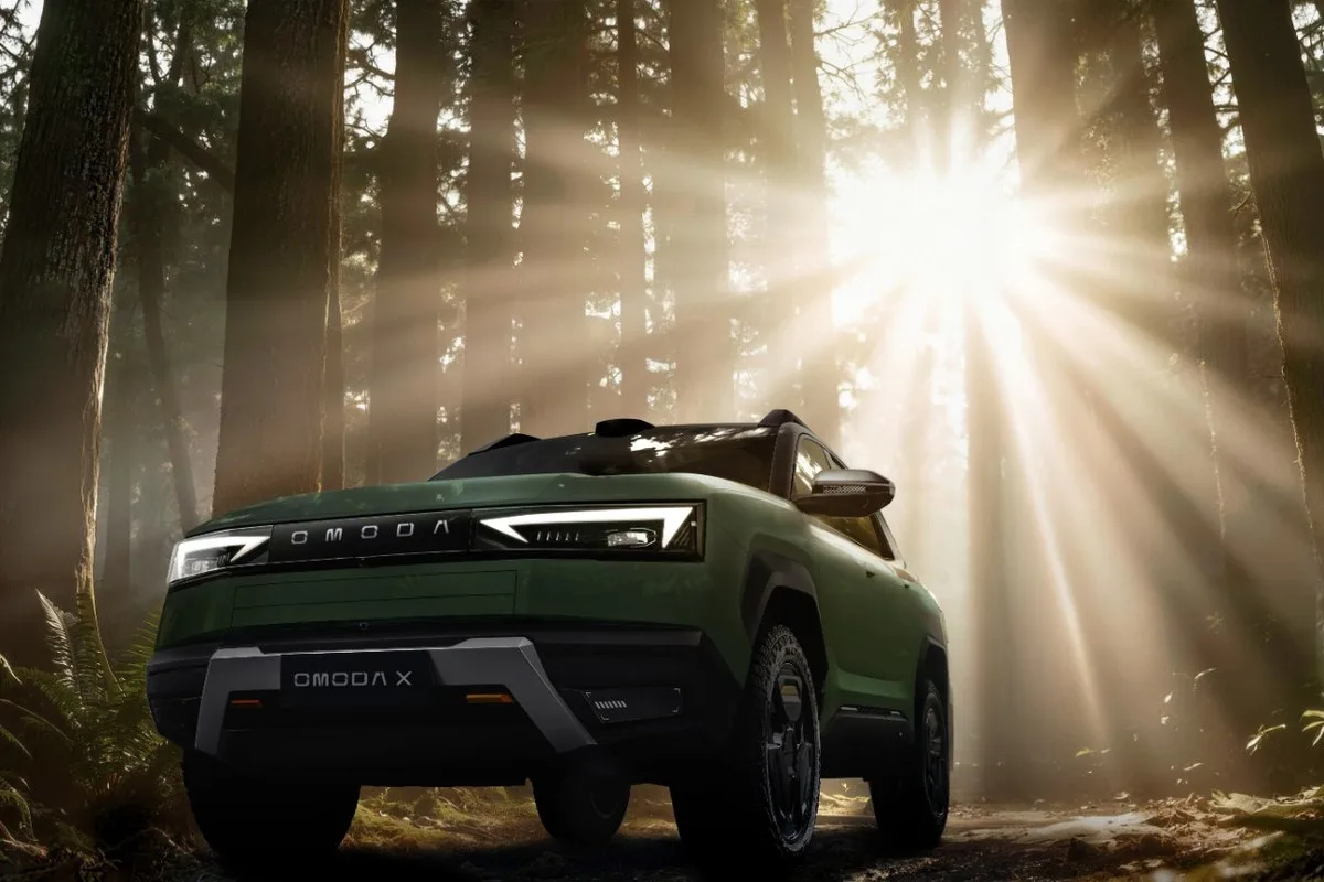 Green Omoda X front view on a forest track with sunlight through tall trees