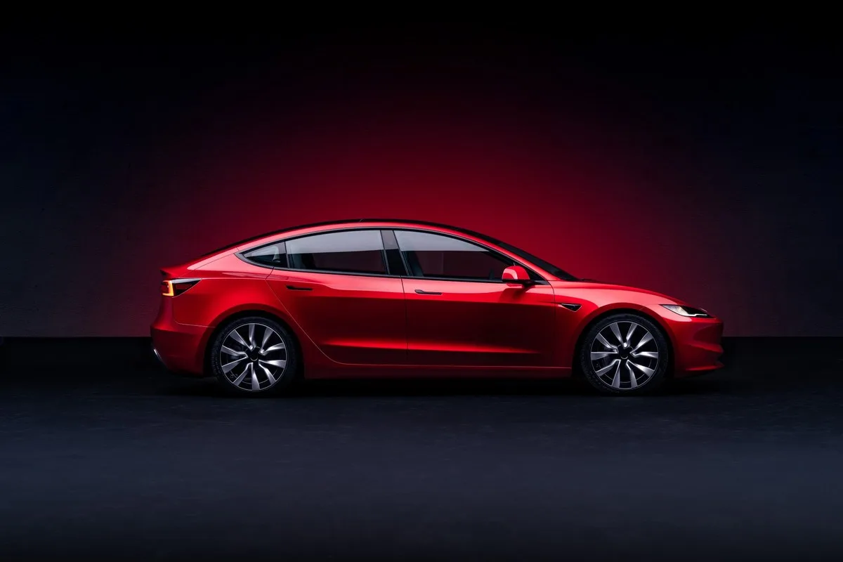 Red Tesla Model 3 side profile against a dark red backdrop