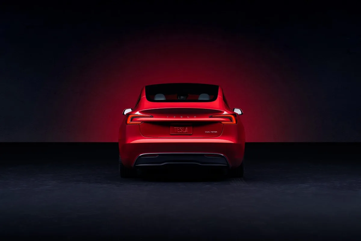 Rear of a red Tesla Model 3 Dual Motor against a dark backdrop