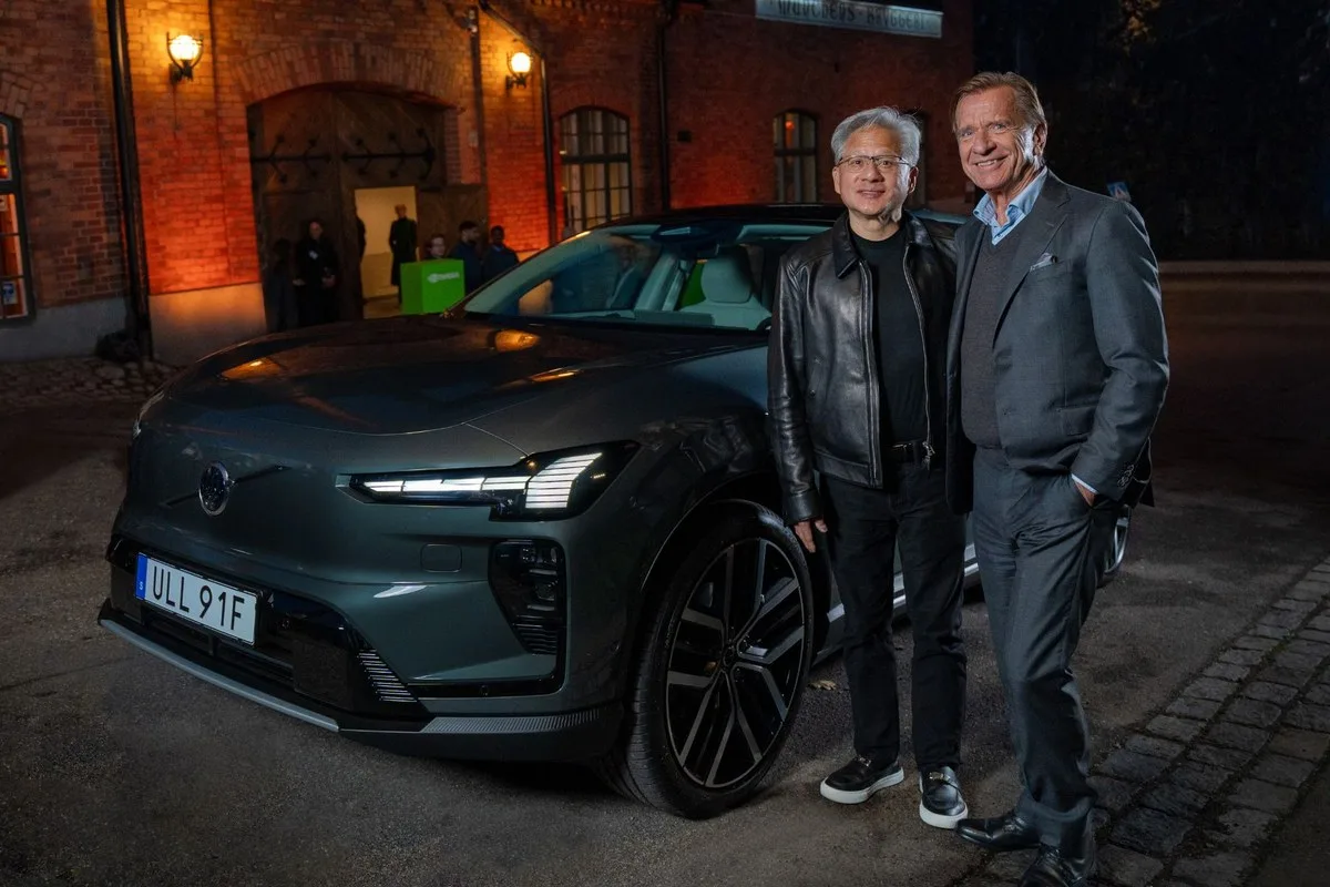 NVIDIA CEO Jensen Huang and Volvo Cars CEO Håkan Samuelsson standing beside a dark grey Volvo EX60 at night